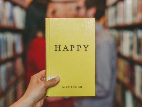 Hand holding up a book titled Happy