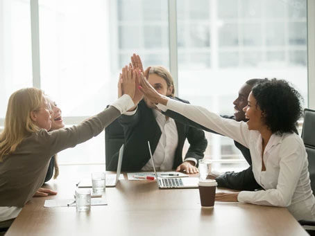 Group giving a high five in office setting